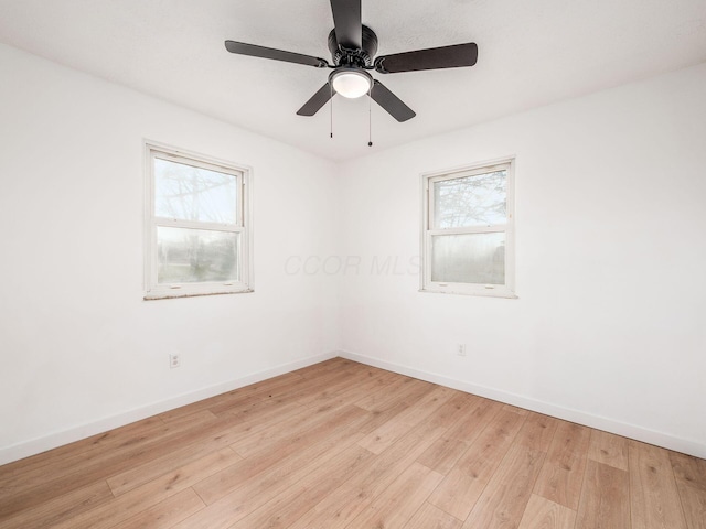 spare room featuring a ceiling fan, baseboards, and light wood finished floors