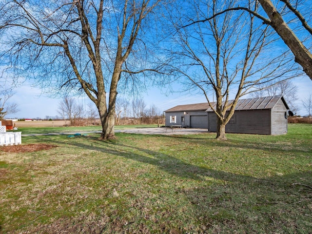 view of yard featuring driveway, an outbuilding, and a garage