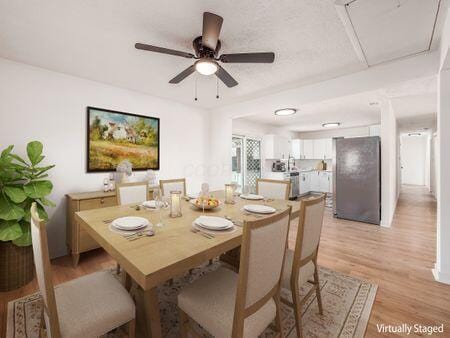 dining area featuring ceiling fan, light wood-style flooring, and attic access
