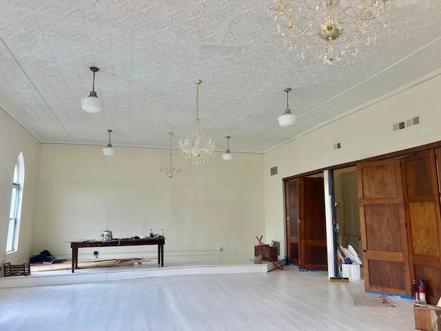 misc room featuring wood finished floors, an inviting chandelier, and visible vents