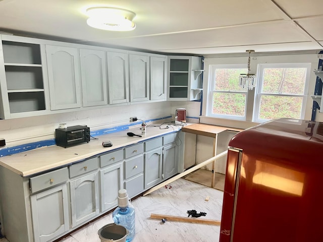 kitchen with gray cabinetry, marble finish floor, light countertops, and open shelves