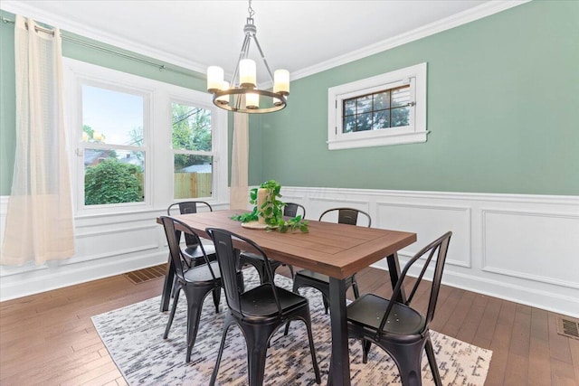 dining space with ornamental molding, a decorative wall, dark wood-style flooring, and a chandelier