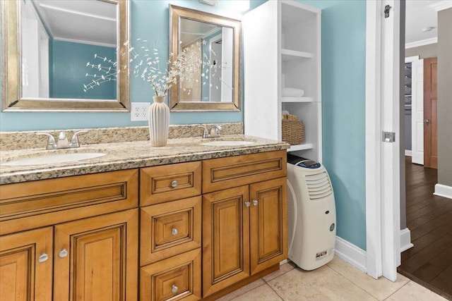 bathroom featuring double vanity, baseboards, ornamental molding, and a sink