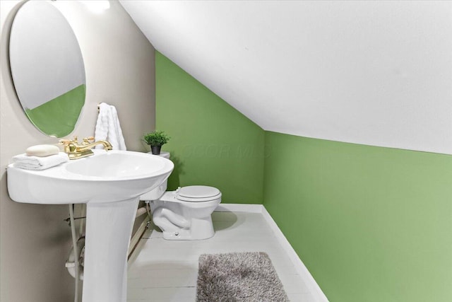 bathroom with baseboards, vaulted ceiling, and toilet