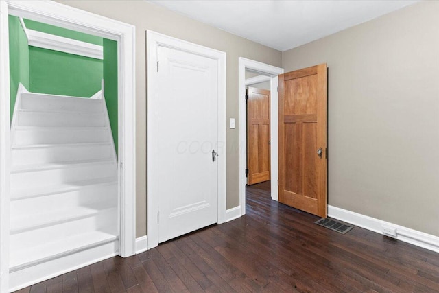 staircase with baseboards, visible vents, and hardwood / wood-style floors