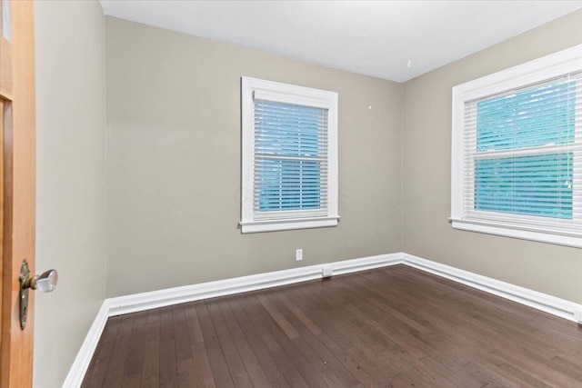 unfurnished room featuring baseboards and dark wood-style floors