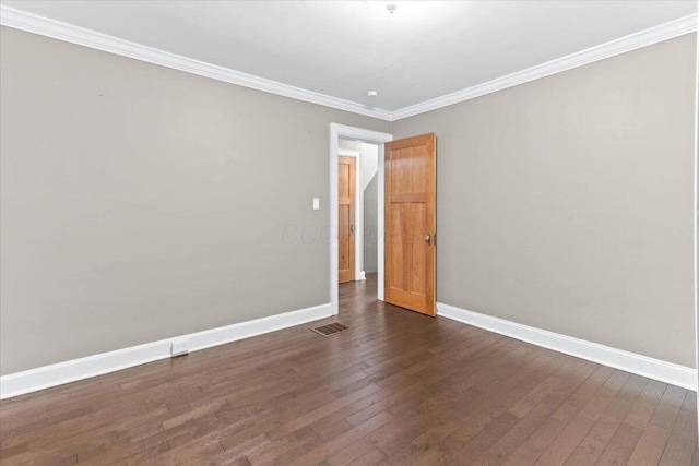 empty room featuring baseboards, crown molding, dark wood-type flooring, and visible vents