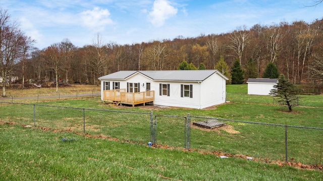 view of front of property with metal roof, a fenced backyard, a forest view, a front yard, and a deck