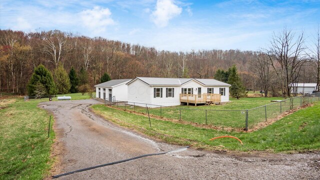 view of front of home with fence, a front yard, a wooded view, and aphalt driveway