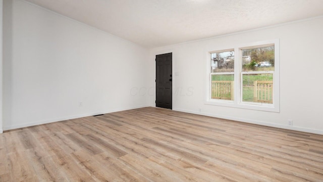 unfurnished room featuring crown molding, baseboards, a textured ceiling, visible vents, and light wood-style flooring