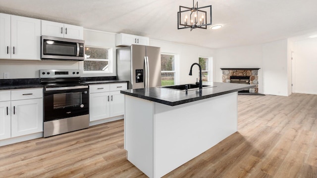 kitchen with a sink, dark countertops, appliances with stainless steel finishes, and a notable chandelier
