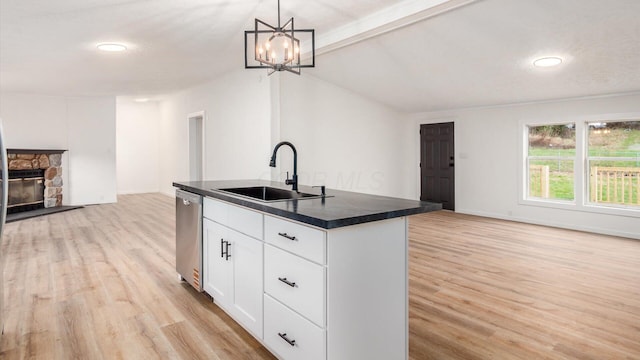 kitchen featuring open floor plan, a sink, dark countertops, dishwasher, and a kitchen island with sink