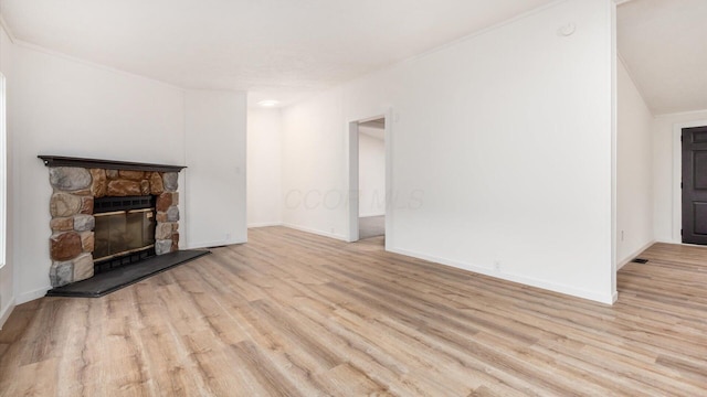 unfurnished living room with a stone fireplace, baseboards, and wood finished floors
