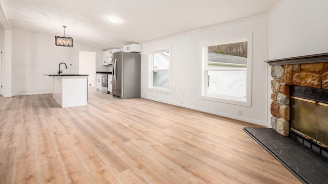 unfurnished living room with a chandelier, baseboards, a stone fireplace, lofted ceiling, and light wood-type flooring