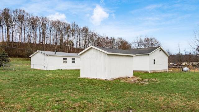 view of side of property with a lawn, fence, and an outdoor structure