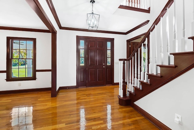 foyer featuring stairway, ornamental molding, baseboards, a notable chandelier, and wood finished floors