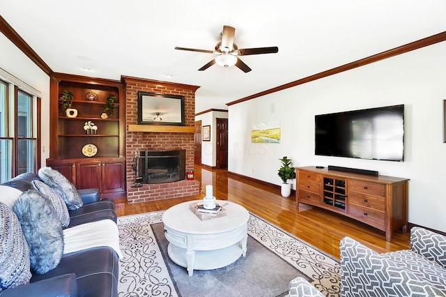 living room featuring a brick fireplace, ornamental molding, baseboards, a ceiling fan, and wood finished floors