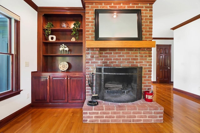 unfurnished living room featuring crown molding, baseboards, a fireplace, and wood finished floors