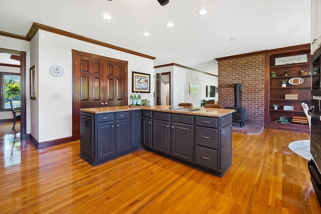 kitchen with light stone counters, baseboards, light wood finished floors, and a wood stove