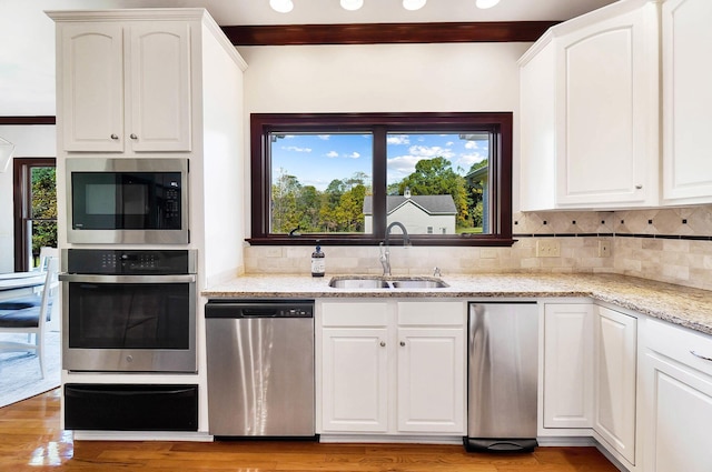 kitchen featuring tasteful backsplash, appliances with stainless steel finishes, white cabinetry, a sink, and a warming drawer