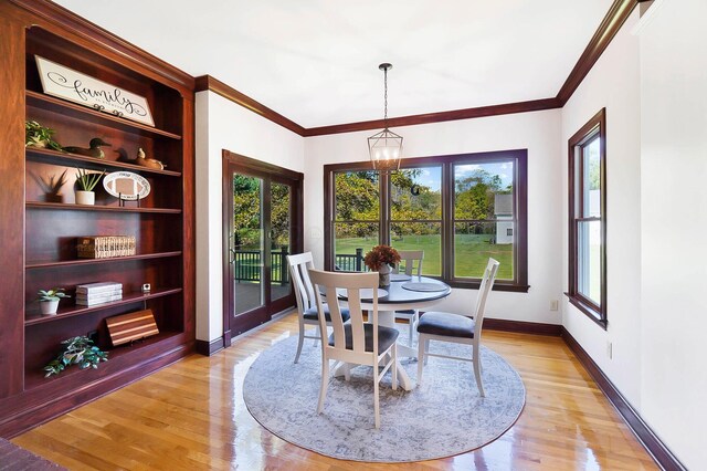 dining space featuring ornamental molding, baseboards, a notable chandelier, and light wood-type flooring