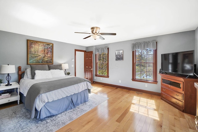 bedroom featuring baseboards, visible vents, light wood-style floors, and a ceiling fan