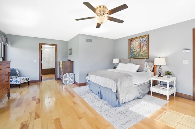 bedroom with a ceiling fan, light wood-type flooring, ensuite bath, baseboards, and visible vents