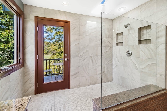 full bath with plenty of natural light, tile walls, and a walk in shower