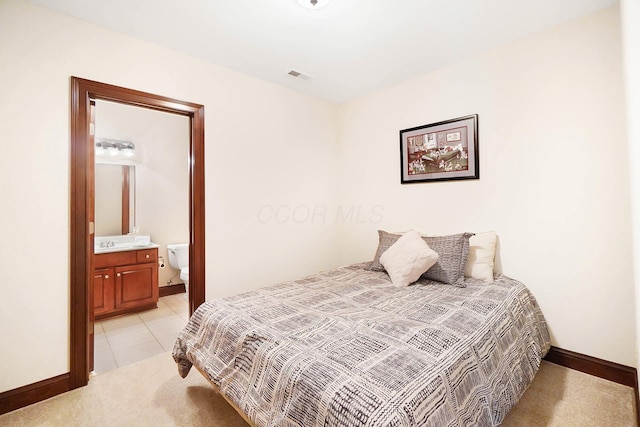bedroom featuring light tile patterned floors, baseboards, visible vents, light carpet, and ensuite bathroom