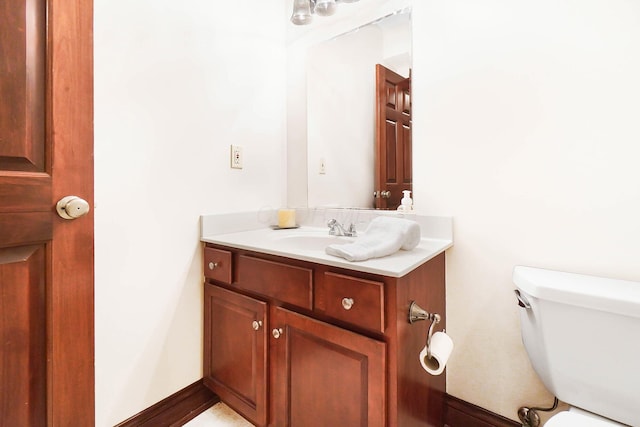 bathroom featuring toilet, vanity, and baseboards