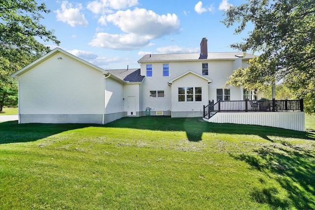 back of property with a chimney, a wooden deck, and a yard