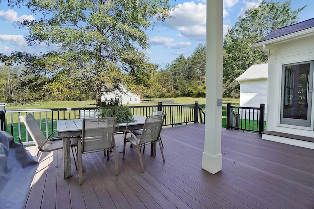 deck featuring outdoor dining space and a lawn