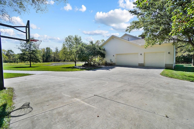 exterior space featuring an attached garage, concrete driveway, and a yard