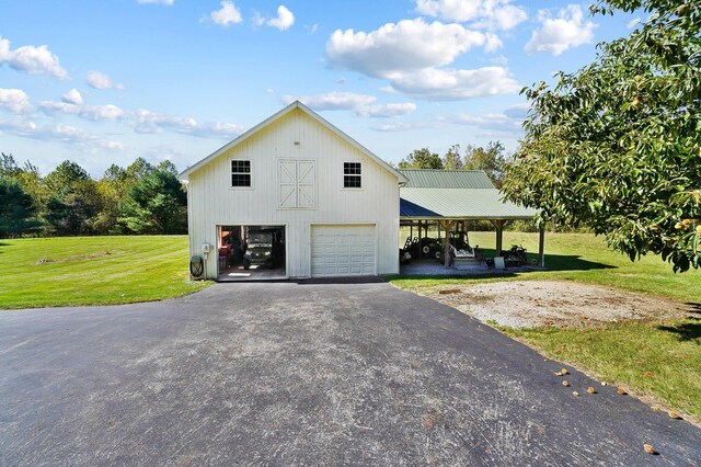 view of side of property with a detached garage, aphalt driveway, and a lawn