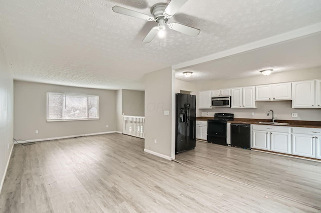 3104 Lewis Rd, Columbus, OH 43207 - kitchen with black appliances, dark countertops, a textured ceiling, light wood-style flooring, and open floor plan