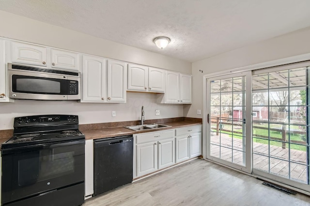 3104 Lewis Rd, Columbus, OH 43207 - kitchen with black appliances, light wood-style flooring, dark countertops, white cabinetry, and a textured ceiling