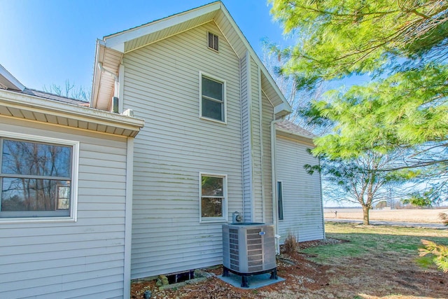 view of side of home featuring cooling unit and a shingled roof