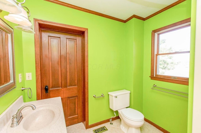 half bathroom featuring crown molding, toilet, a sink, tile patterned flooring, and baseboards