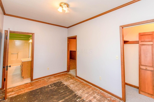 unfurnished bedroom featuring a closet, connected bathroom, baseboards, and crown molding