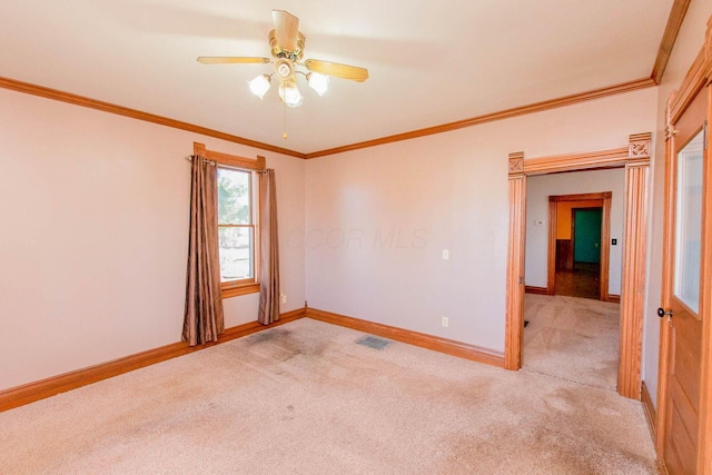 spare room featuring light colored carpet, crown molding, and baseboards