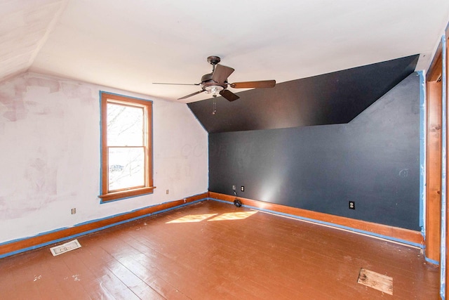 additional living space with vaulted ceiling, wood-type flooring, baseboards, visible vents, and ceiling fan