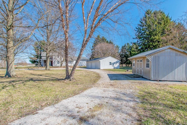 view of yard featuring an outdoor structure, driveway, and a detached garage