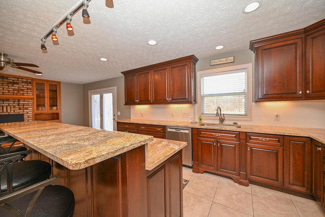 kitchen with tasteful backsplash, a breakfast bar area, stainless steel dishwasher, a sink, and ceiling fan