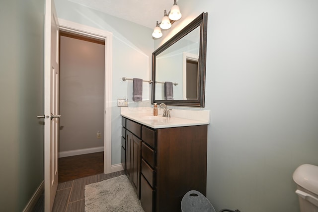 bathroom featuring toilet, vanity, and baseboards