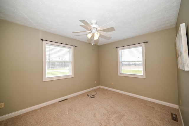carpeted empty room with a wealth of natural light, visible vents, and baseboards