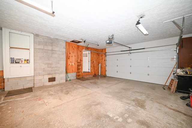 garage featuring concrete block wall and a garage door opener