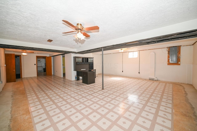 below grade area featuring a textured ceiling, electric panel, a ceiling fan, and light floors
