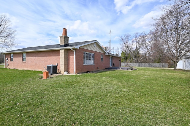 view of property exterior featuring fence, a chimney, central AC, brick siding, and a yard