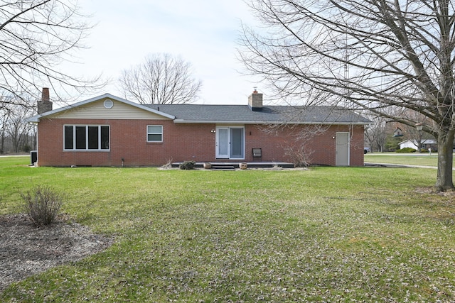 back of property with a lawn, a chimney, and brick siding