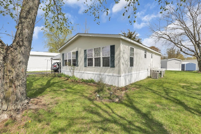view of side of property featuring an outbuilding, cooling unit, and a lawn